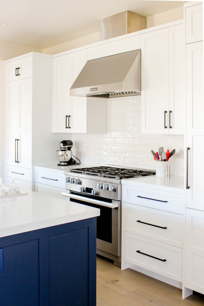 Kitchen - transitional beige floor kitchen idea with shaker cabinets, subway tile backsplash, stainless steel appliances, an island and white countertops
