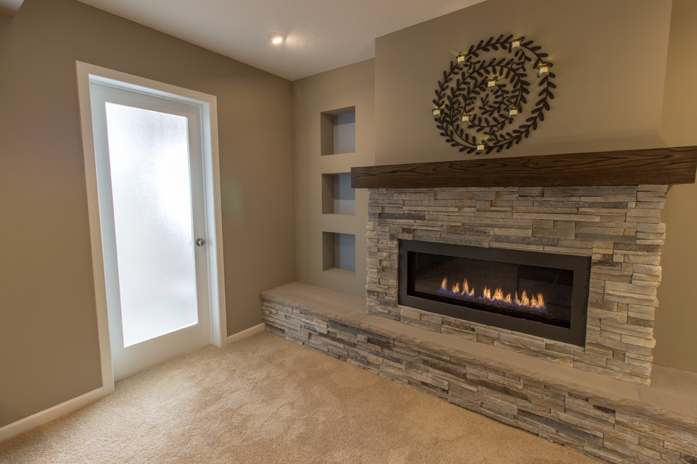Transitional look-out basement in Minneapolis with beige walls, carpet, a standard fireplace, a stone fireplace surround and beige floor.