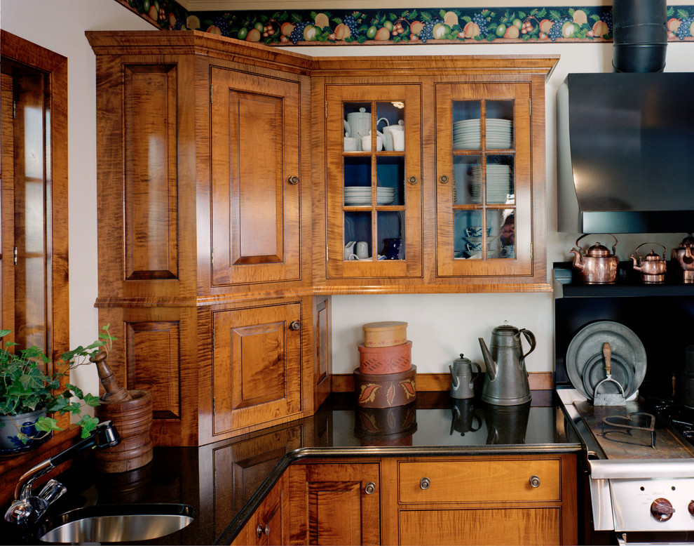 Inspiration for a mid-sized traditional kitchen in Boston with a double-bowl sink, beaded inset cabinets, medium wood cabinets, granite benchtops, black appliances, terra-cotta floors and a peninsula.