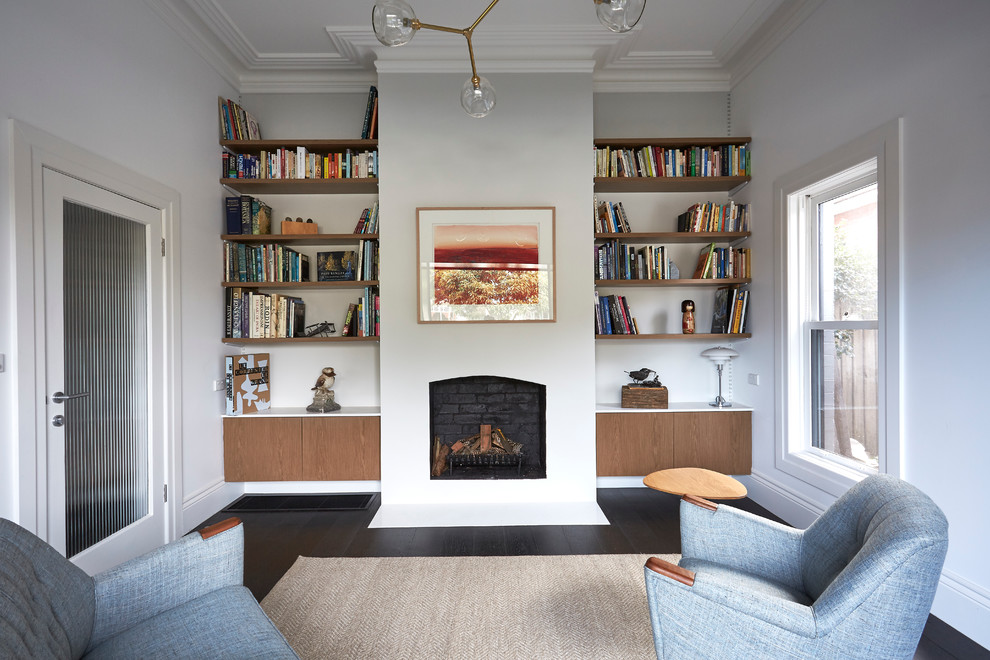 Mid-sized transitional enclosed living room in Melbourne with a library, white walls, dark hardwood floors, a standard fireplace, a plaster fireplace surround and no tv.