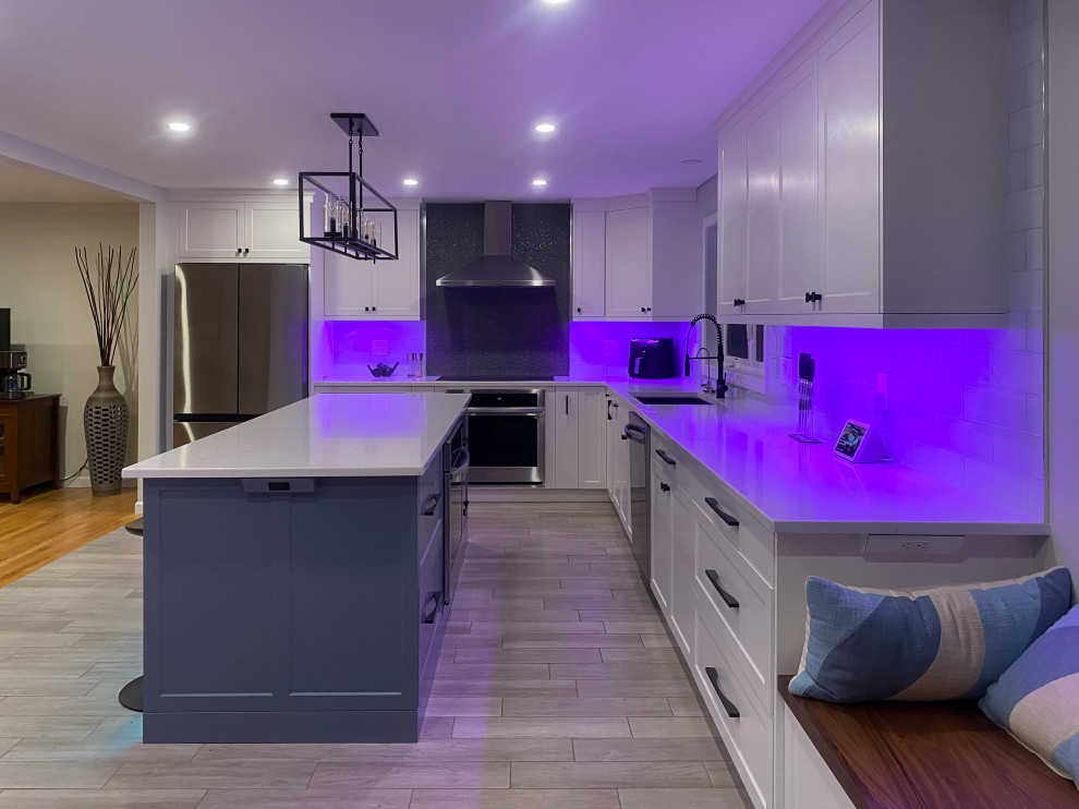 Inspiration for an expansive contemporary l-shaped open plan kitchen in Bridgeport with a submerged sink, shaker cabinets, white cabinets, engineered stone countertops, white splashback, metro tiled splashback, porcelain flooring, an island, grey floors and white worktops.