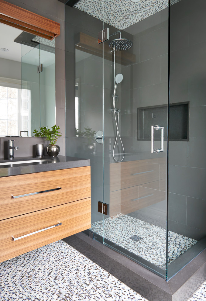 This is an example of a small contemporary 3/4 bathroom in Toronto with flat-panel cabinets, medium wood cabinets, a corner shower, multi-coloured tile, porcelain tile, grey walls, mosaic tile floors, an undermount sink, engineered quartz benchtops and a hinged shower door.