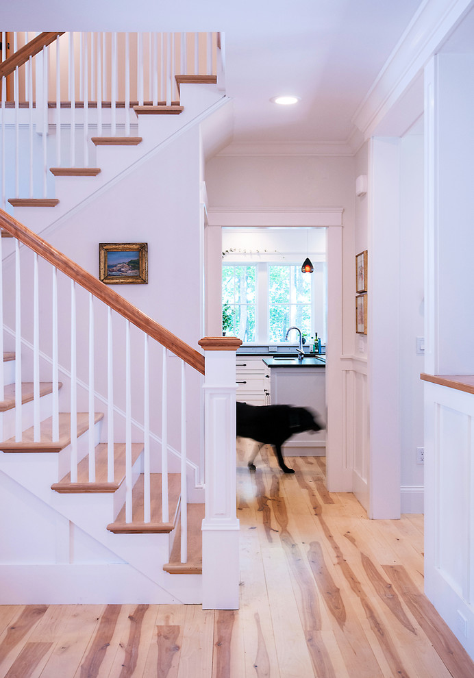 This is an example of a beach style foyer in Other with white walls and light hardwood floors.