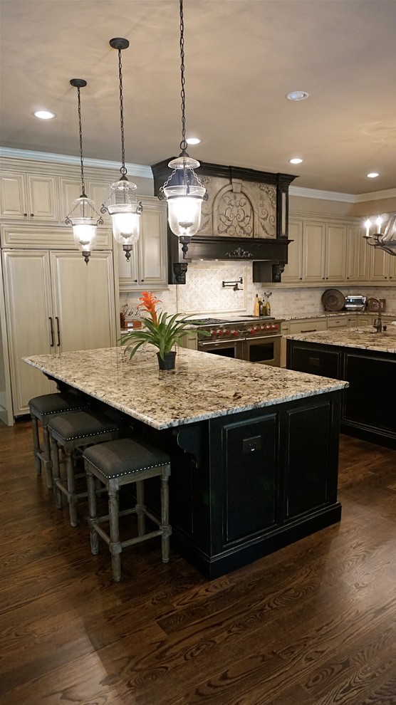 Inspiration for an expansive traditional u-shaped eat-in kitchen in Atlanta with an undermount sink, raised-panel cabinets, distressed cabinets, granite benchtops, beige splashback, subway tile splashback, stainless steel appliances, dark hardwood floors and multiple islands.