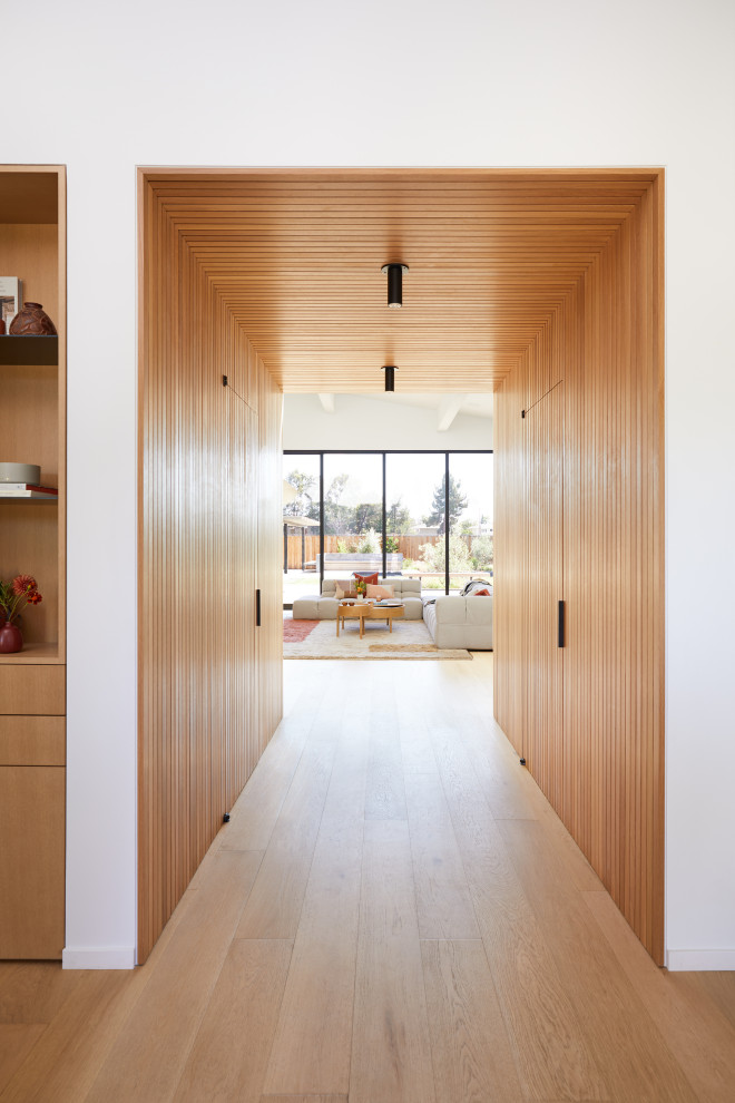 Стильный дизайн: фойе среднего размера в стиле модернизм с белыми стенами, светлым паркетным полом, поворотной входной дверью, входной дверью из светлого дерева, коричневым полом, сводчатым потолком и деревянными стенами - последний тренд