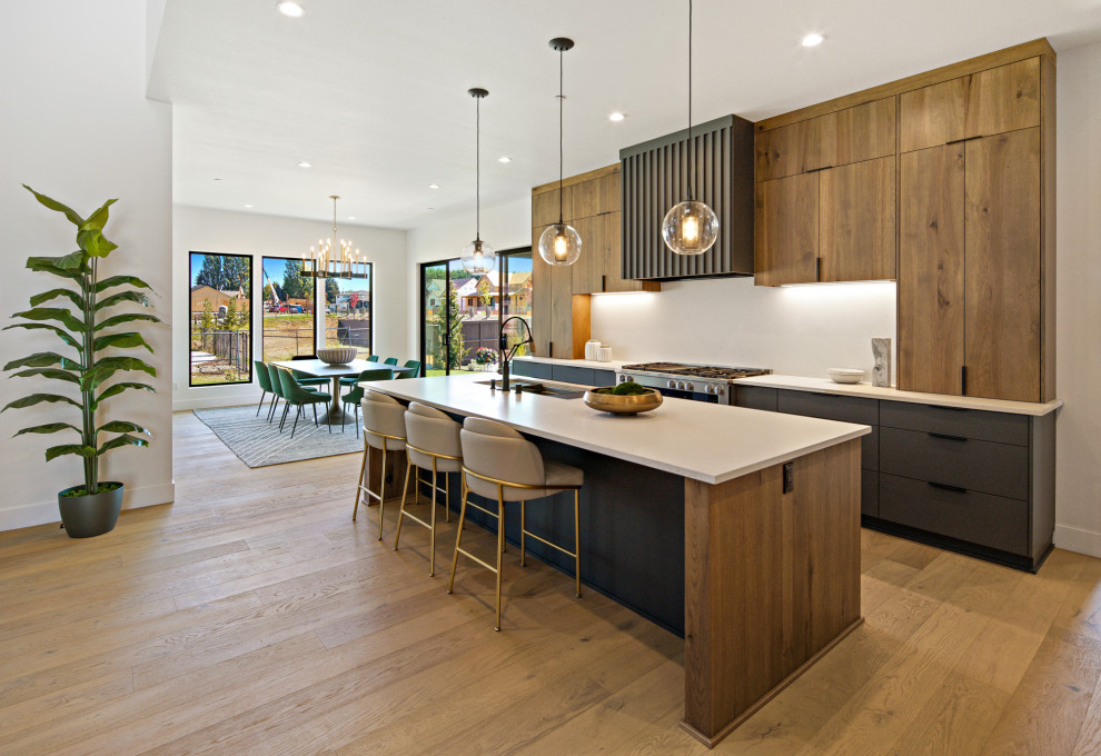 Large trendy single-wall medium tone wood floor and brown floor eat-in kitchen photo in Portland with a drop-in sink, flat-panel cabinets, medium tone wood cabinets, granite countertops, beige backsplash, stainless steel appliances, an island and beige countertops