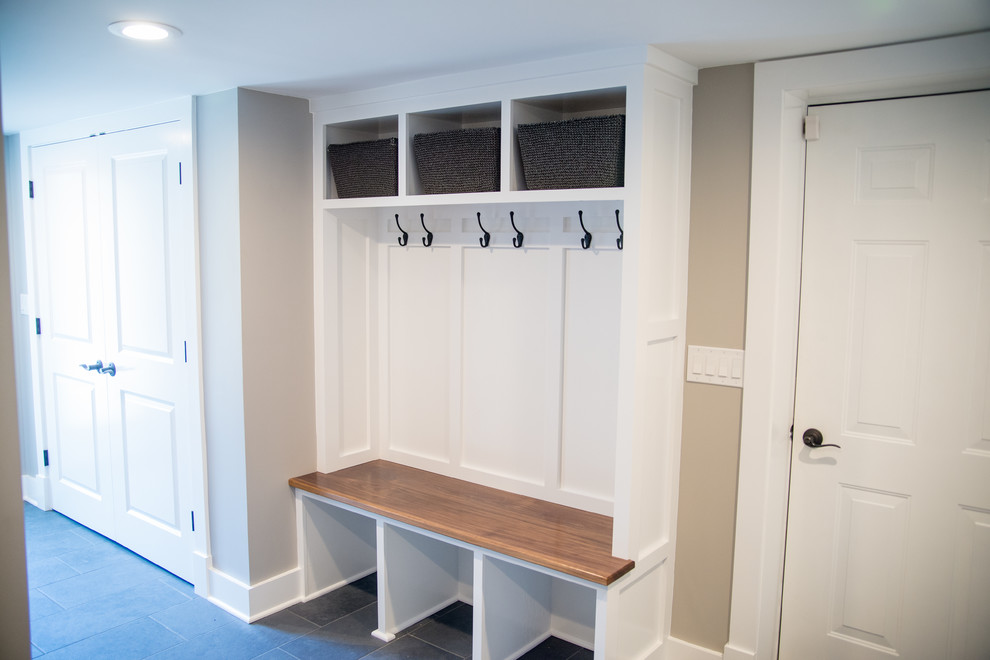 This is an example of a large transitional mudroom in New York with beige walls, slate floors, a single front door and a white front door.