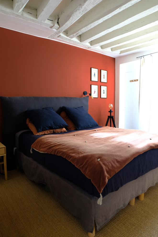 Ejemplo de dormitorio principal bohemio de tamaño medio sin chimenea con paredes rojas, suelo beige y vigas vistas