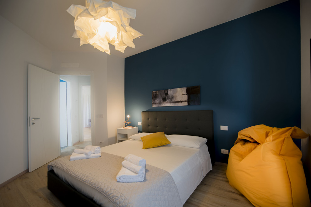Foto di una camera degli ospiti minimalista di medie dimensioni con pareti blu, pavimento in legno verniciato e pavimento marrone
