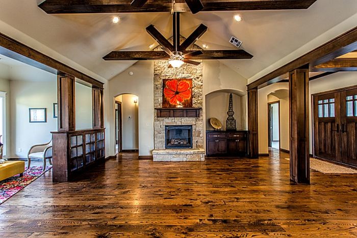 Photo of a mid-sized arts and crafts formal open concept living room in Oklahoma City with beige walls, dark hardwood floors, a standard fireplace, a stone fireplace surround, no tv and brown floor.