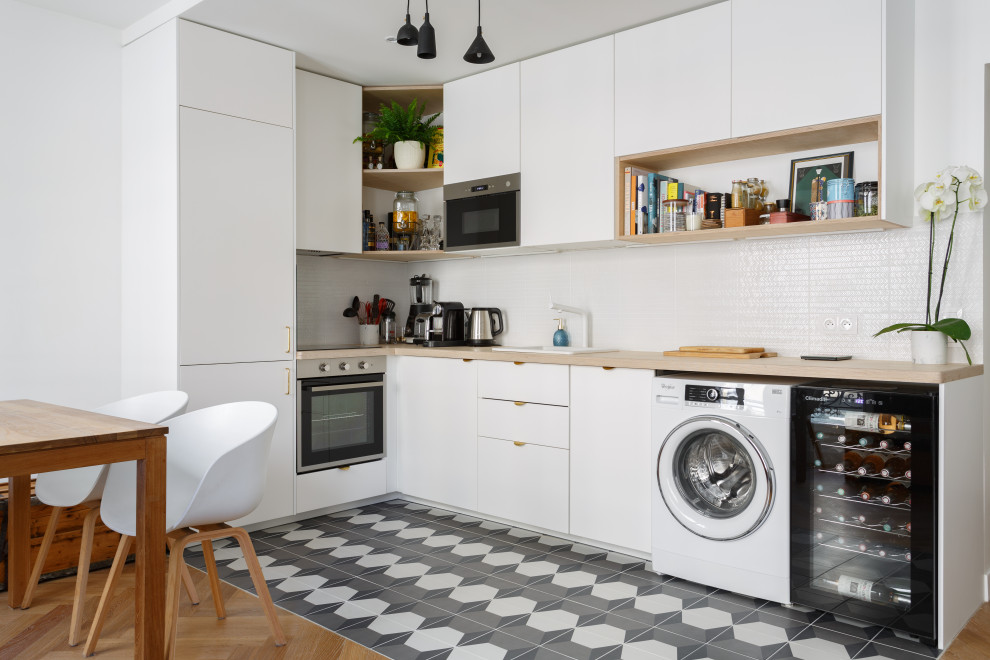 Small scandinavian l-shaped eat-in kitchen in Other with a drop-in sink, flat-panel cabinets, white cabinets, wood benchtops, white splashback, cement tiles, no island, beige benchtop and multi-coloured floor.