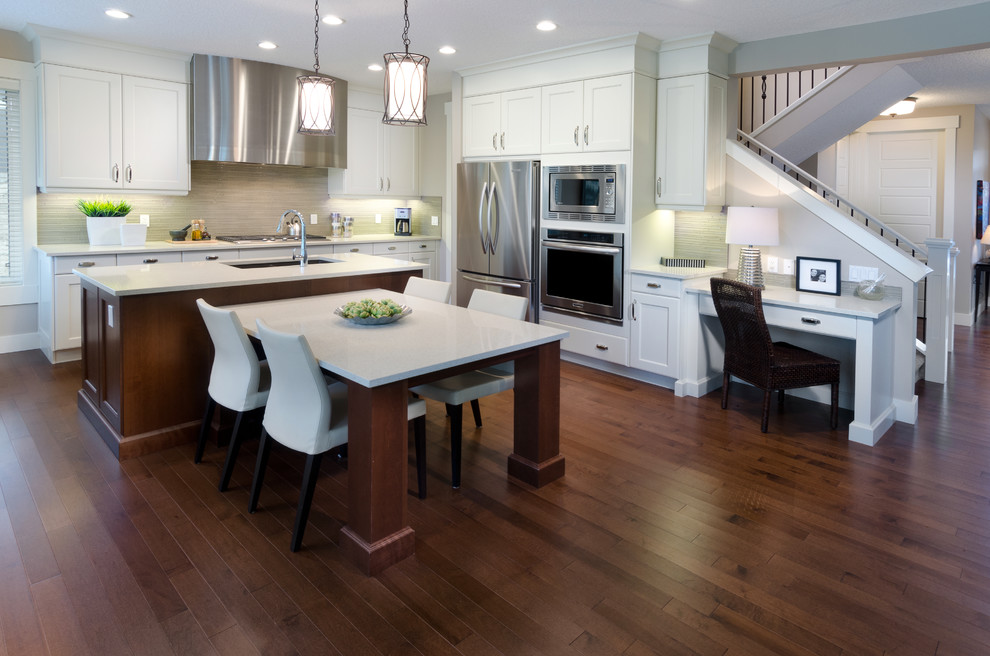 Inspiration for a large transitional l-shaped dark wood floor open concept kitchen remodel in Calgary with an undermount sink, recessed-panel cabinets, white cabinets, solid surface countertops, gray backsplash, glass tile backsplash, stainless steel appliances and an island