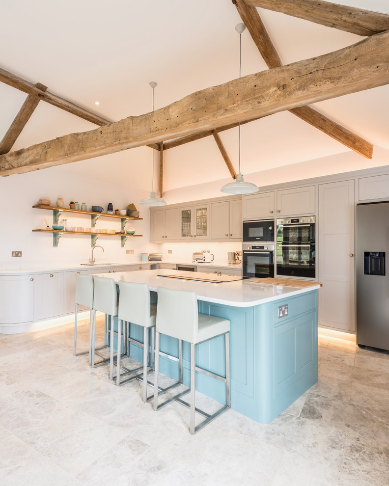Country l-shaped kitchen in Dorset with an undermount sink, shaker cabinets, grey cabinets, stainless steel appliances, with island and grey floor.