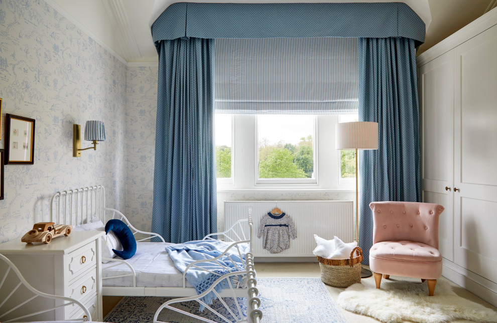 This is an example of a medium sized traditional gender neutral toddler’s room in London with blue walls, carpet, beige floors, a coffered ceiling and wallpapered walls.