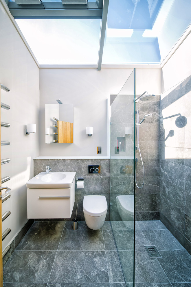 Small contemporary 3/4 bathroom in Other with white cabinets, gray tile, ceramic floors, flat-panel cabinets, a curbless shower, grey walls, a wall-mount toilet, a wall-mount sink and an open shower.
