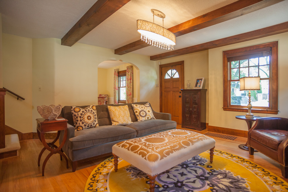 This is an example of a mid-sized country living room in Detroit with beige walls, light hardwood floors, a standard fireplace, a brick fireplace surround and brown floor.