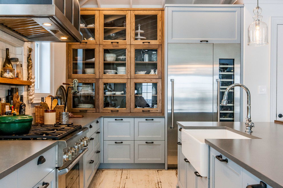Inspiration for a large country l-shaped kitchen in Other with a farmhouse sink, recessed-panel cabinets, grey cabinets, white splashback, subway tile splashback, stainless steel appliances, painted wood floors, with island, white floor and grey benchtop.