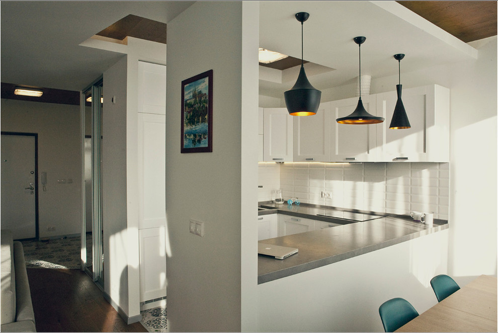 This is an example of a small contemporary u-shaped open plan kitchen in Moscow with an undermount sink, white cabinets, white splashback, ceramic splashback, stainless steel appliances, ceramic floors and with island.