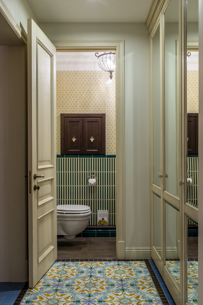 This is an example of a mid-sized traditional powder room in Moscow with a wall-mount toilet, green tile, yellow tile, ceramic tile, porcelain floors and brown floor.