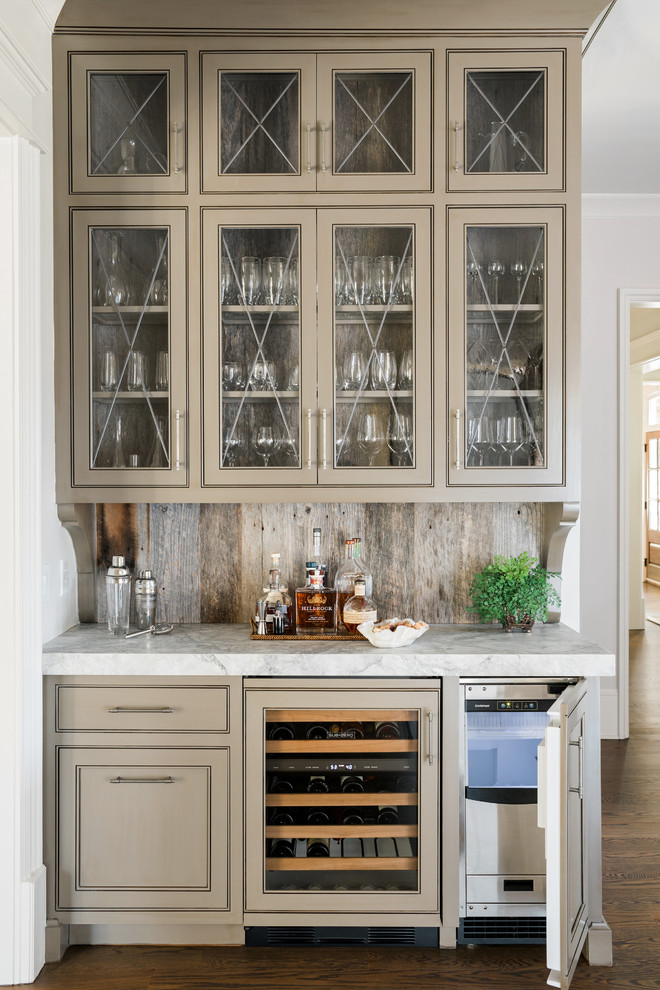 Inspiration for a traditional single-wall home bar in Atlanta with no sink, glass-front cabinets, beige cabinets, timber splashback and dark hardwood floors.
