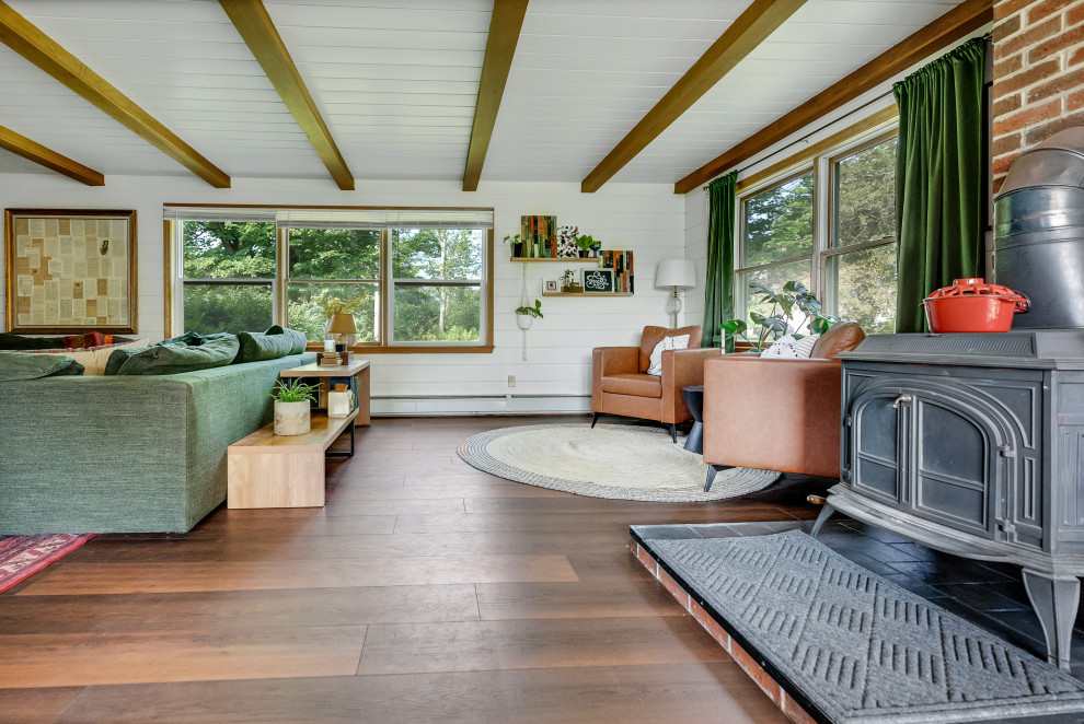 Photo of a small eclectic formal open concept living room in Portland Maine with white walls, vinyl floors, a wood stove, a metal fireplace surround, a wall-mounted tv, brown floor, coffered and panelled walls.