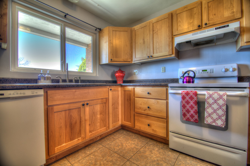 This is an example of a small u-shaped separate kitchen in Albuquerque with a double-bowl sink, shaker cabinets, light wood cabinets, laminate benchtops, blue splashback, white appliances, ceramic floors and no island.