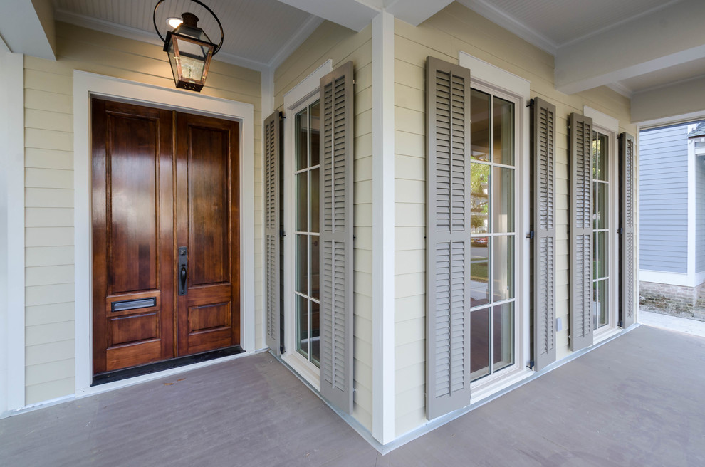 This is an example of a large traditional front yard verandah in New Orleans with decking and a roof extension.