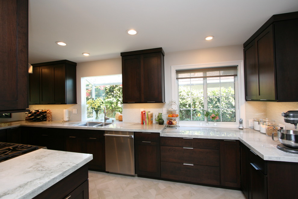 Mid-sized transitional l-shaped porcelain tile kitchen photo in Orange County with a double-bowl sink, recessed-panel cabinets, dark wood cabinets, quartzite countertops, white backsplash, glass tile backsplash, stainless steel appliances and no island