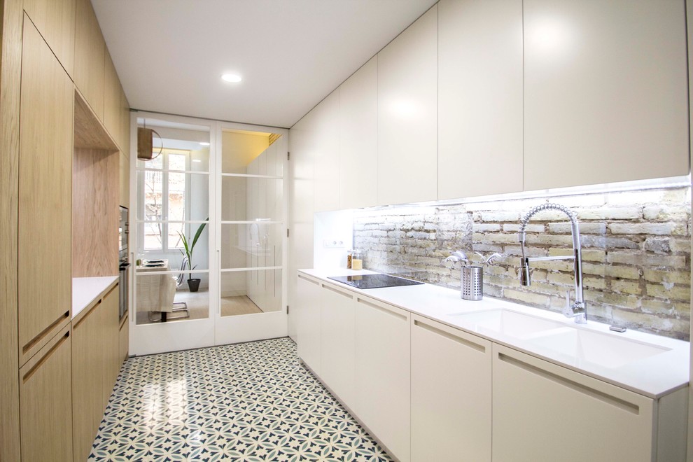 Mid-sized contemporary single-wall separate kitchen in Valencia with a double-bowl sink, flat-panel cabinets, white cabinets, panelled appliances, ceramic floors, no island and white benchtop.