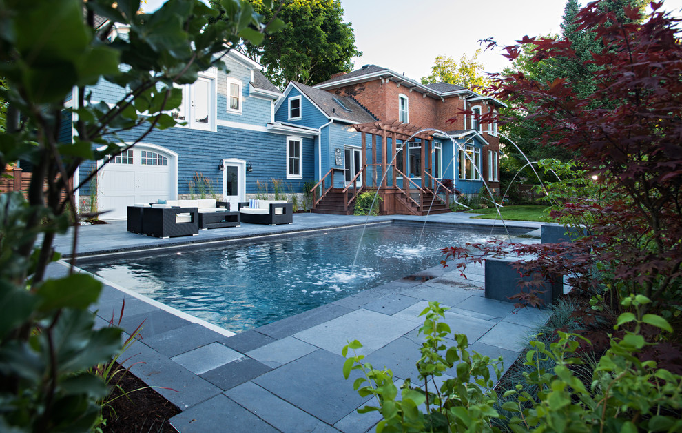 Example of a transitional backyard concrete paver pool fountain design in Toronto
