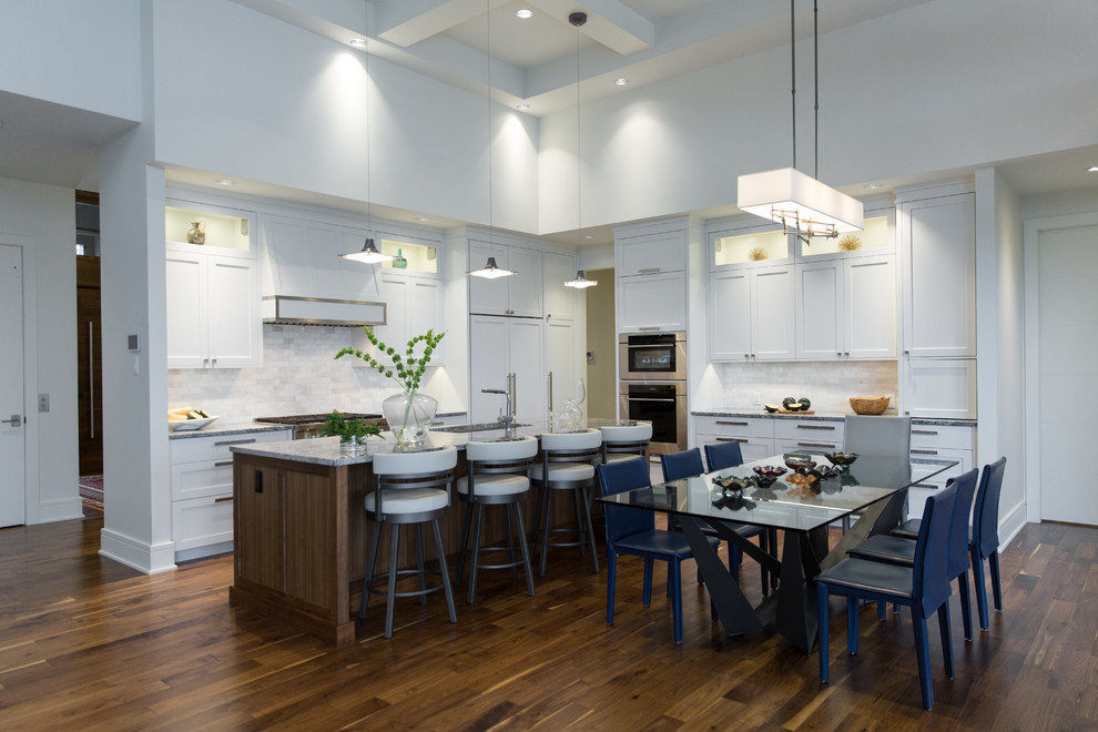 Inspiration for a mid-sized transitional l-shaped medium tone wood floor eat-in kitchen remodel in Vancouver with shaker cabinets, white cabinets, white backsplash, white appliances, an island, granite countertops and an undermount sink