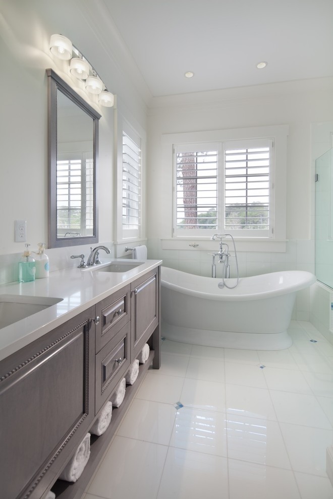 This is an example of a large beach style bathroom in DC Metro with an undermount sink, beaded inset cabinets, brown cabinets, a freestanding tub, a two-piece toilet, white tile, ceramic tile, white walls, ceramic floors and a corner shower.