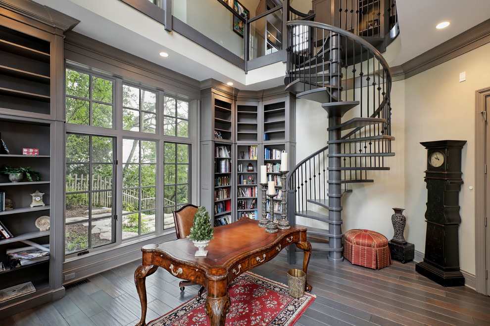 Inspiration for a large traditional home office in Chicago with a library, white walls, dark hardwood floors, no fireplace, a freestanding desk and brown floor.