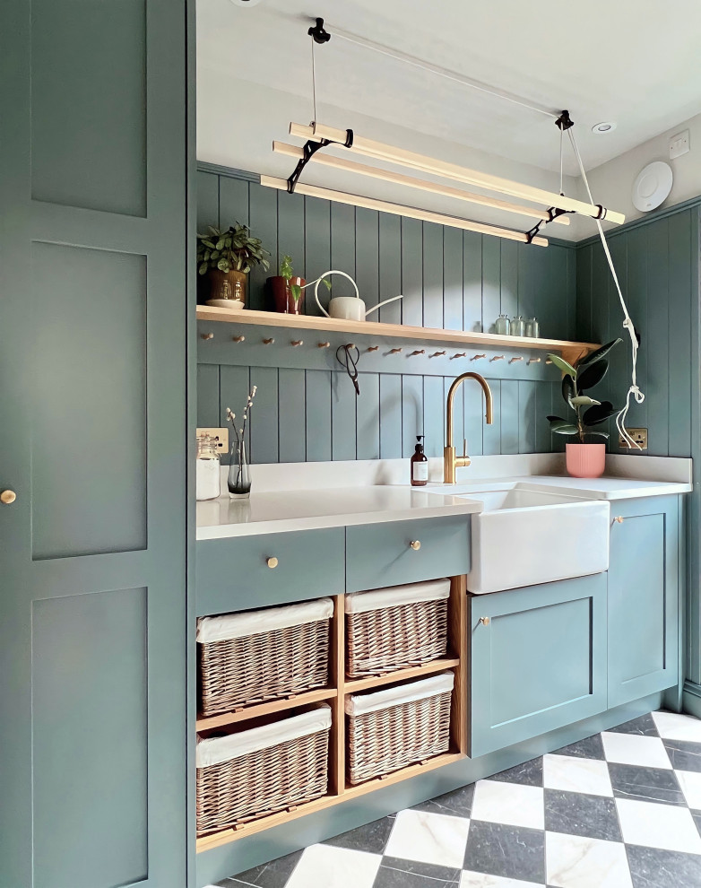 This is an example of a small traditional laundry room in Other with a farmhouse sink, shaker cabinets, blue cabinets, quartzite benchtops, blue walls, porcelain floors, a stacked washer and dryer, white benchtop and planked wall panelling.