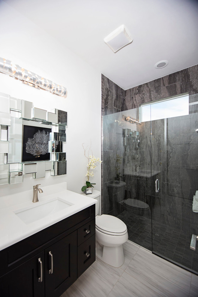 Large modern 3/4 bathroom in Miami with recessed-panel cabinets, grey cabinets, a freestanding tub, a curbless shower, a two-piece toilet, gray tile, stone tile, white walls, marble floors, an undermount sink and solid surface benchtops.