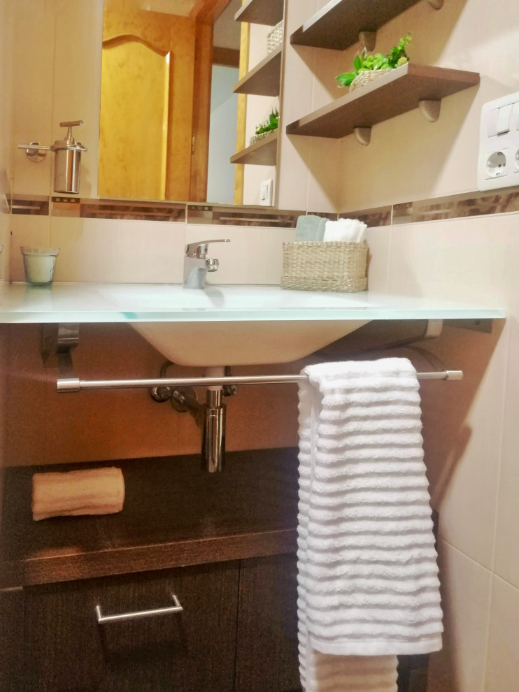 Exempel på ett litet klassiskt vit vitt badrum med dusch, med öppna hyllor, vita skåp, en dusch i en alkov, beige kakel, keramikplattor, beige väggar, klinkergolv i keramik, ett väggmonterat handfat, bänkskiva i glas, brunt golv och dusch med gångjärnsdörr