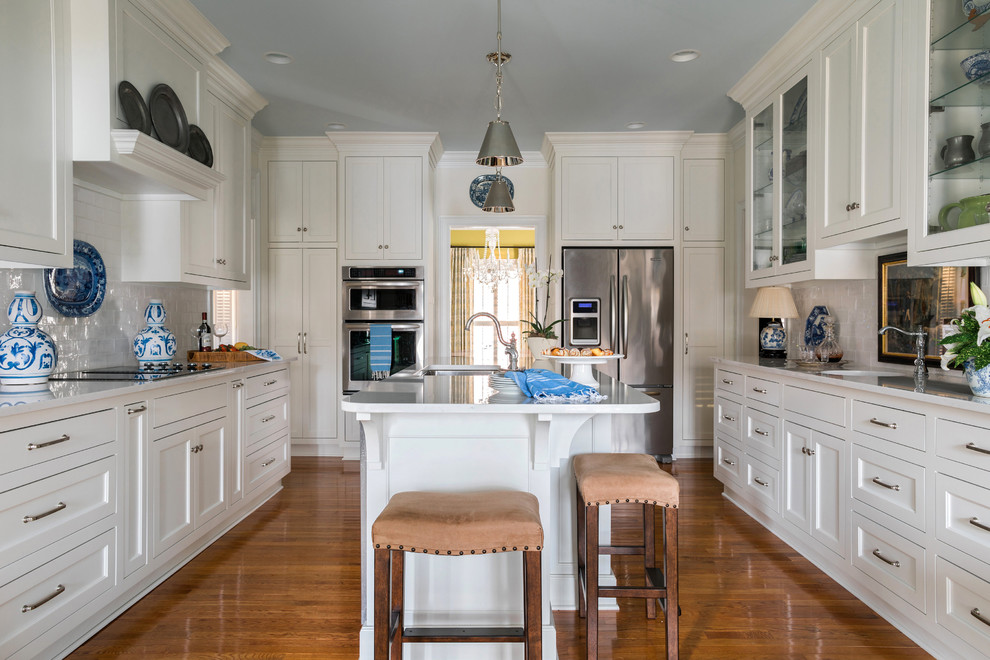 Photo of a mid-sized transitional galley kitchen in Atlanta with an undermount sink, recessed-panel cabinets, turquoise cabinets, quartz benchtops, white splashback, subway tile splashback, stainless steel appliances, medium hardwood floors and with island.