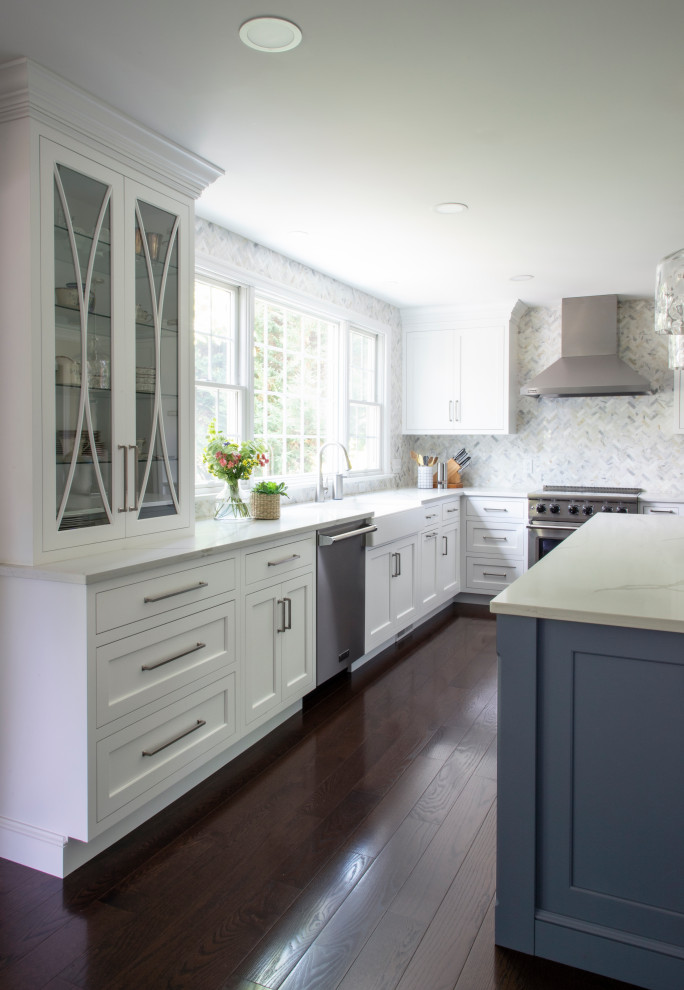 Bild på ett vintage vit vitt kök, med en rustik diskho, luckor med infälld panel, vita skåp, bänkskiva i kvarts, grått stänkskydd, stänkskydd i mosaik, rostfria vitvaror och en köksö
