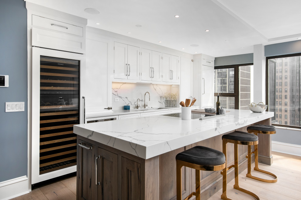 This is an example of a mid-sized transitional single-wall eat-in kitchen in Chicago with an undermount sink, beaded inset cabinets, white cabinets, quartz benchtops, white splashback, engineered quartz splashback, panelled appliances, light hardwood floors, with island, brown floor, white benchtop and coffered.