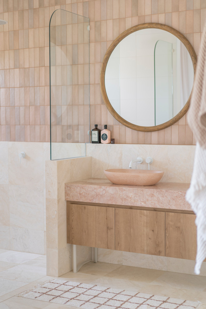 Cette image montre une grande salle de bain minimaliste en bois brun avec un carrelage rose, un plan de toilette en marbre, un plan de toilette rose et meuble simple vasque.