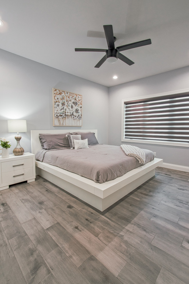Schlafzimmer mit lila Wandfarbe, braunem Holzboden und grauem Boden in Sonstige