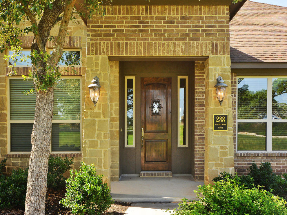 This is an example of a mid-sized country one-storey brick beige house exterior in Austin with a hip roof and a shingle roof.