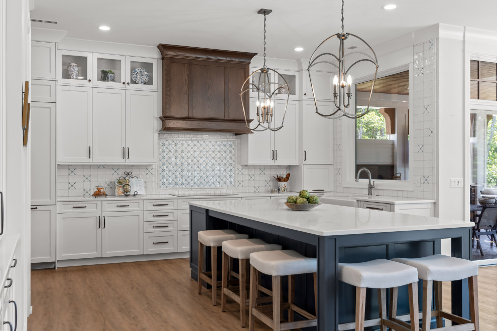Kitchen - mid-sized farmhouse u-shaped medium tone wood floor and brown floor kitchen idea with a farmhouse sink, shaker cabinets, white cabinets, multicolored backsplash, paneled appliances, an island and white countertops