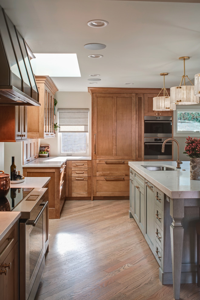 Mid-sized transitional l-shaped medium tone wood floor and brown floor open concept kitchen photo in Chicago with an undermount sink, shaker cabinets, medium tone wood cabinets, quartz countertops, white backsplash, ceramic backsplash, stainless steel appliances, an island and white countertops