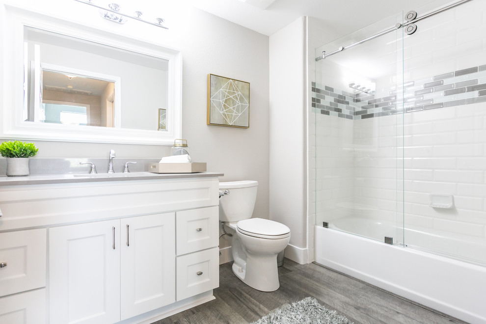 Transitional 3/4 bathroom in Other with shaker cabinets, grey cabinets, an alcove tub, a shower/bathtub combo, a two-piece toilet, gray tile, white tile, subway tile, white walls, an undermount sink, grey floor, a sliding shower screen and grey benchtops.