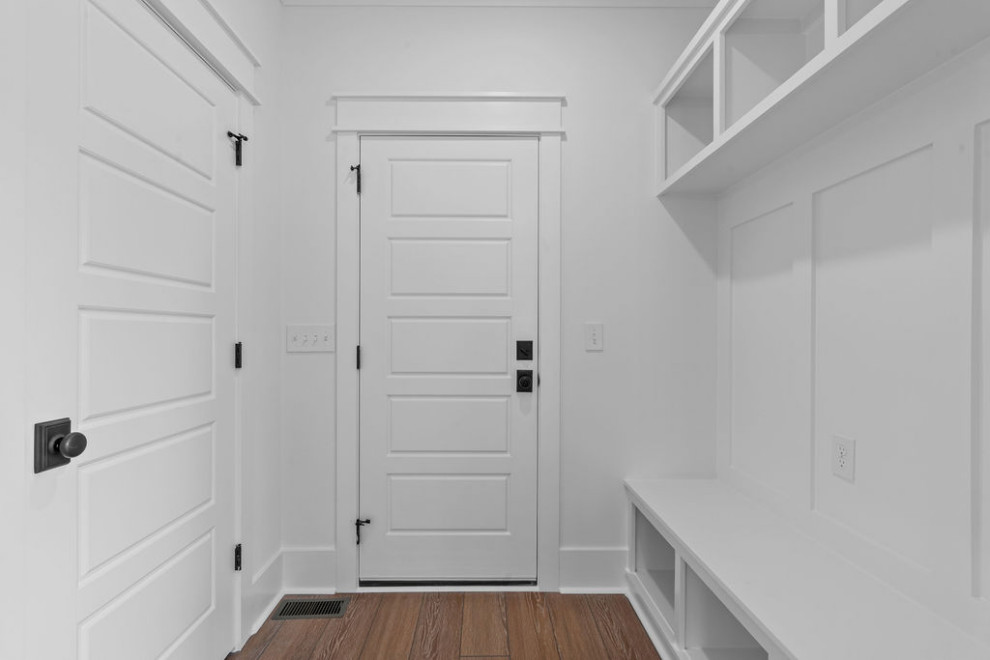Cette image montre une entrée traditionnelle avec un vestiaire, un mur blanc, un sol en vinyl, une porte simple, une porte blanche et un sol marron.