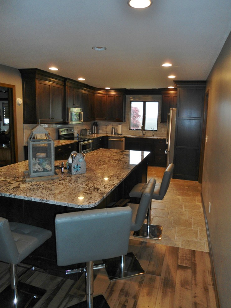 Mid-sized transitional u-shaped eat-in kitchen photo with an undermount sink, flat-panel cabinets, dark wood cabinets, granite countertops, gray backsplash, subway tile backsplash, stainless steel appliances and an island
