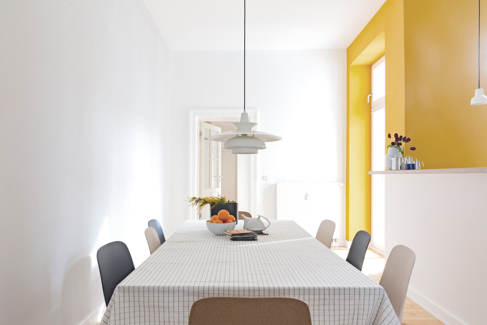 Inspiration for a mid-sized contemporary dining room in Berlin with yellow walls and light hardwood floors.