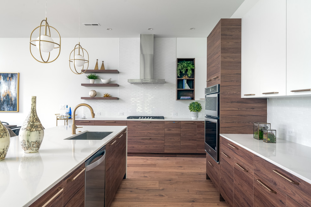 This is an example of a contemporary l-shaped kitchen in Charlotte with an undermount sink, flat-panel cabinets, medium wood cabinets, quartz benchtops, white splashback, ceramic splashback, stainless steel appliances, laminate floors, with island and white benchtop.