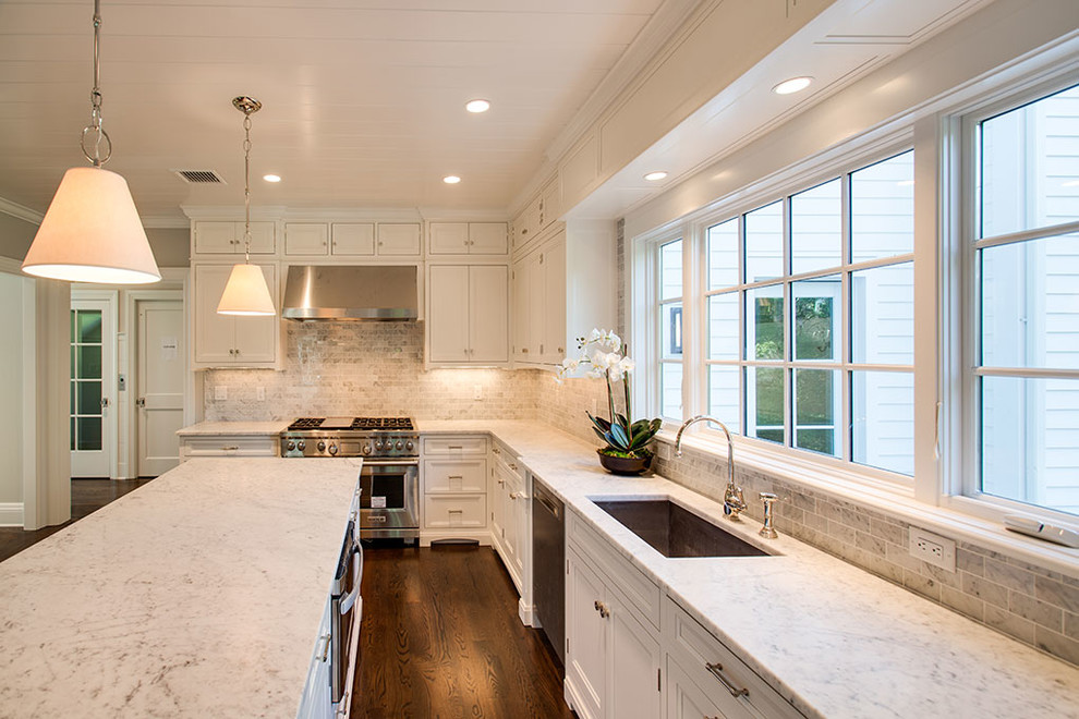 Large transitional u-shaped dark wood floor and brown floor eat-in kitchen photo with an undermount sink, recessed-panel cabinets, white cabinets, white backsplash, stainless steel appliances and an island